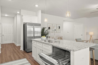 Kitchen featuring a sink, freestanding refrigerator, a kitchen breakfast bar, white cabinets, and dark wood-style floors