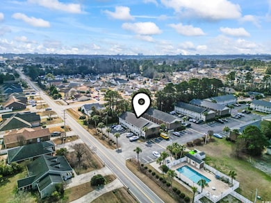 Aerial view of property and surrounding area featuring nearby suburban area and a pool area