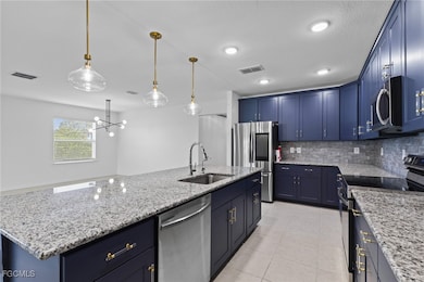 Kitchen with appliances with stainless steel finishes, a kitchen island with sink, light stone countertops, a textured ceiling, and recessed lighting