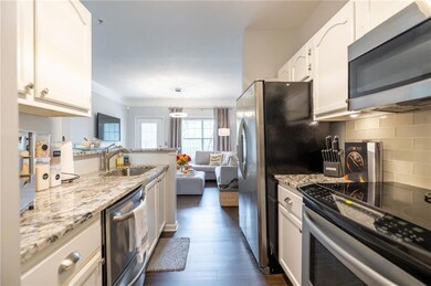 Kitchen with appliances with stainless steel finishes, baseboards, dark wood-style floors, white cabinetry, and tasteful backsplash