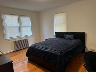 Bedroom featuring radiator, crown molding, and wood finished floors