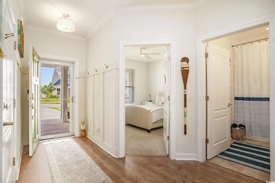 Foyer with light wood finished floors, ornamental molding, and a ceiling fan