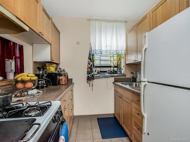 Kitchen featuring freestanding refrigerator, light tile patterned floors, gas stove, baseboards, and a sink