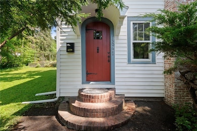 Charming front entrance with brick steps and arched portico.