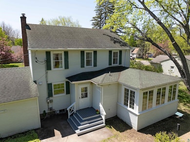 View of front facade with a chimney and a shingled roof