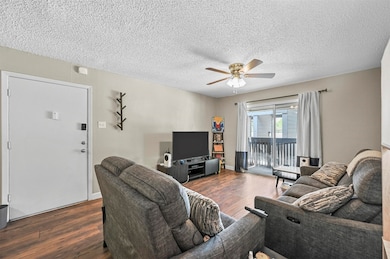 Living area featuring wood finished floors, a textured ceiling, and ceiling fan