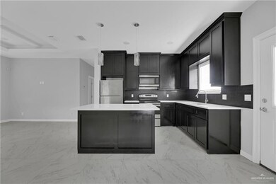 Kitchen with light tile flooring, a kitchen island, stainless steel appliances, backsplash, and pendant lighting