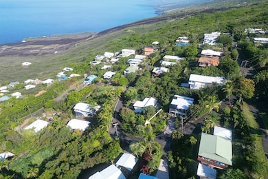 Elevated perspective of surrounding homes and tropical greenery within the Kona Paradise community with the ocean just beyond