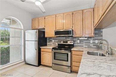 Kitchen with stainless steel appliances, light brown cabinets, sink, and backsplash