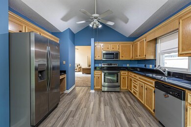 Kitchen with a sink, dark wood-type flooring, dark countertops, and appliances with stainless steel finishes