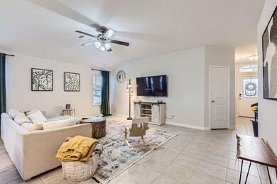 Living room with ceiling fan and light tile patterned flooring
