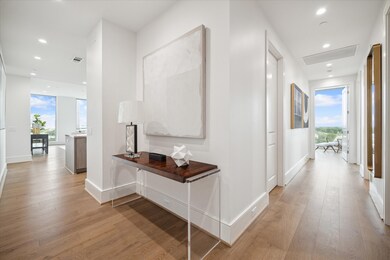 Featuring wide-plank hardwood floors and soaring ceilings, the entryway sets the tone for the home’s contemporary style. Photos are of a similar unit with the same floor plan