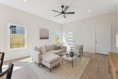Living room featuring light wood-type flooring, recessed lighting, and a ceiling fan