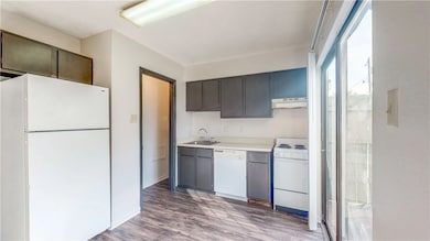 Kitchen featuring a sink, white appliances, light