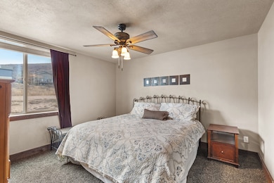 Carpeted bedroom featuring a textured ceiling and a ceiling fan