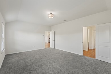 Unfurnished bedroom featuring lofted ceiling and carpet flooring, and door to ensuite bathroom