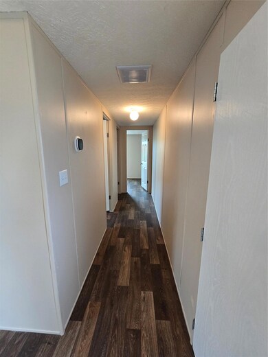 Hallway with a textured ceiling, wood finished fl