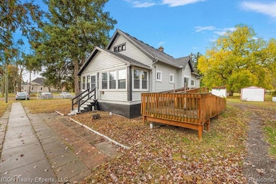Rear view of property featuring a deck, a storage unit, and a yard
