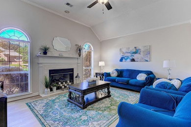 Living room featuring crown molding, wood finished floors, healthy amount of natural light, lofted ceiling, and a fireplace