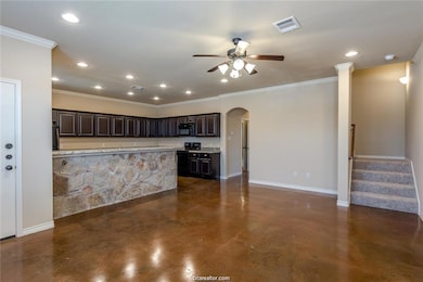 Kitchen with arched walkways, visible vents, baseboards, finished concrete flooring, and black appliances