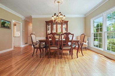 Dining space with a chandelier, light wood finished floors, healthy amount of natural light, and ornamental molding