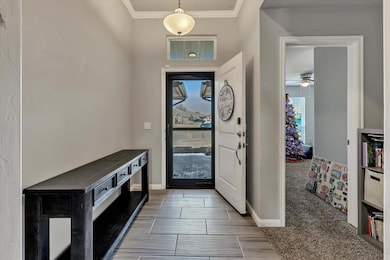 Entrance foyer featuring crown molding, wood tiled floors, a ceiling fan, and light carpet