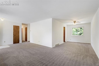 Carpeted empty room with a ceiling fan and baseboards