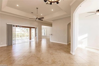 Tiled empty room with crown molding, a raised ceil