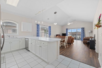 Kitchen featuring open floor plan, light tile patterned flooring, appliances with stainless steel finishes, a ceiling fan, and vaulted ceiling