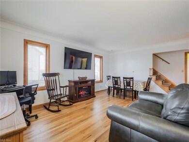 Living room featuring a wealth of natural light, light wood-type flooring, crown molding, and a fireplace