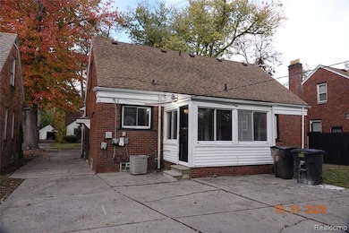 Rear view of property featuring a patio area, roof with shingles, brick siding, entry steps, and a sunroom