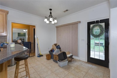 Dining room with light tile patterned floors, ornamental molding, and a chandelier