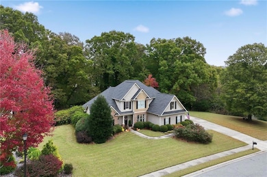 View of front of property featuring a front lawn, driveway, and a wooded view
