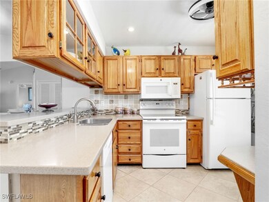 Kitchen with a sink, white appliances, backsplash,