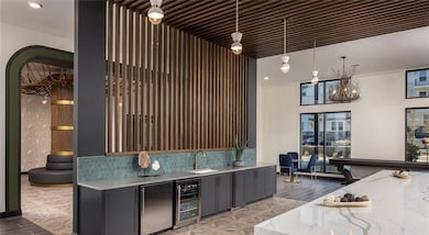 Indoor bar with beverage cooler, light wood finished floors, crown molding, tasteful backsplash, and fridge