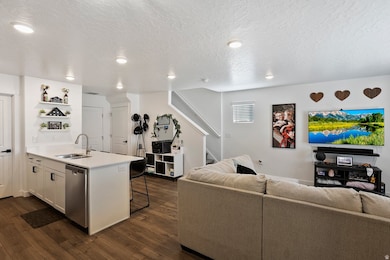 Kitchen with a peninsula, dark wood-type flooring, open floor plan, white cabinetry, and a textured ceiling