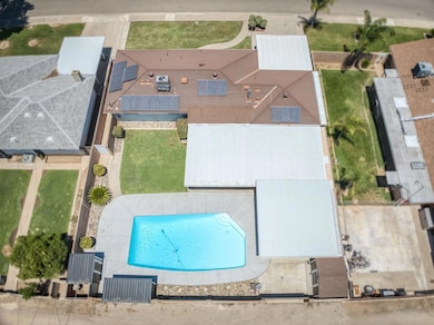 Large 9200 sq.ft. lot with sparkling pool and 18 panels of owned solar. Notice extended patio area and 3 storage sheds.