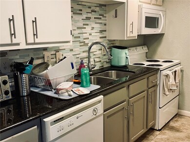 Kitchen with a sink, dark stone counters, white ap