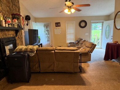 Carpeted living area featuring ceiling fan and a f