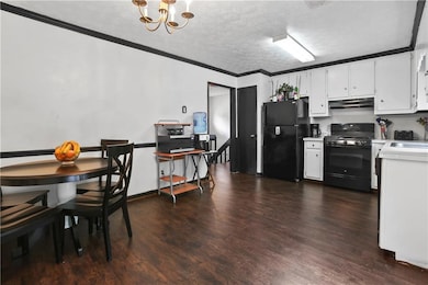 Kitchen with black appliances, under cabinet range hood, light countertops, a textured ceiling, and a chandelier