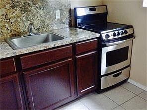 Kitchen featuring electric stove, a sink, light c