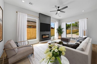 Living room with a large fireplace, light hardwood
