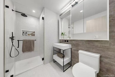 Bathroom with a stall shower, vanity, and tile walls