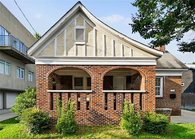 View of front of house with brick siding, a porch, and a chimney