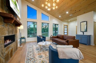 Living area with high vaulted ceiling, light wood-
