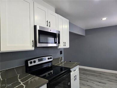 Kitchen featuring white cabinetry, baseboards, dar