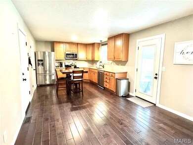 Kitchen with stainless steel appliances, dark wood-type flooring, light countertops, and a textured ceiling