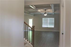 Hallway with coffered ceiling, baseboards, beam ceiling, and stairs