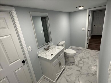 Full bath with marble look tiles, double vanity, and toilet