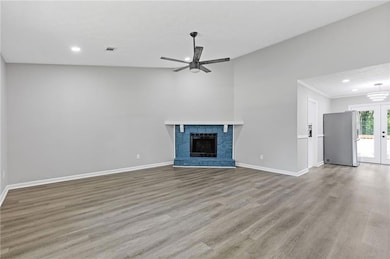 Unfurnished living room featuring a ceiling fan, recessed lighting, wood finished floors, a stone fireplace, and french doors